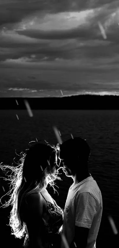 Black and white silhouette of a couple at a lake, with a dramatic cloudy sky.