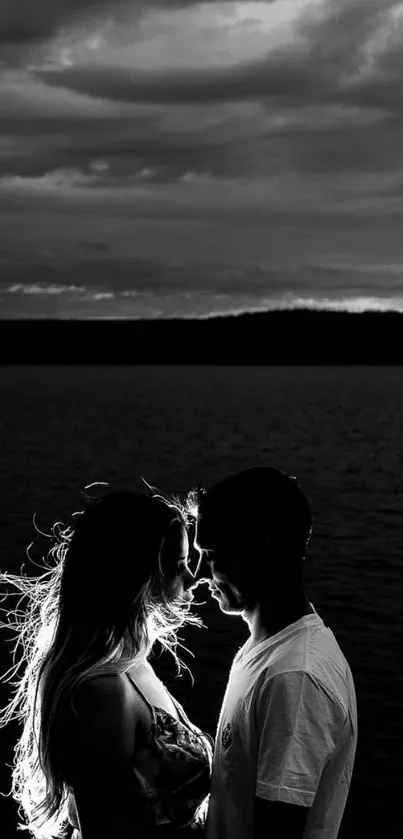 Romantic couple silhouette at sunset by the ocean in monochrome tones.