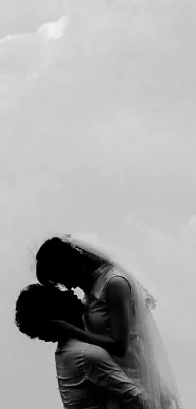 Silhouette of a couple kissing against a cloudy sky.