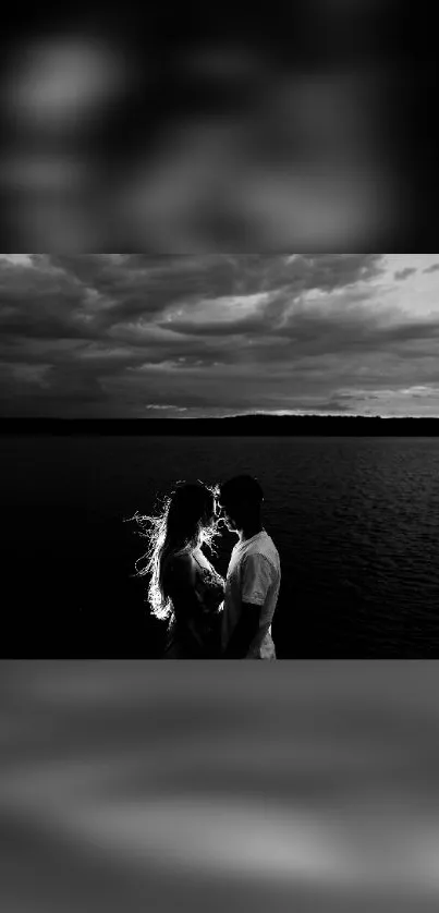 Silhouette of a couple by a lake with dramatic clouds.