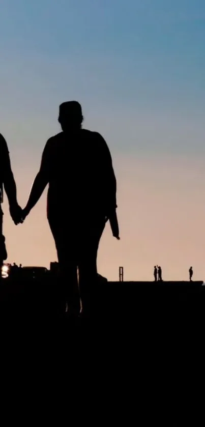 Silhouette of couple holding hands at sunset on a beach.