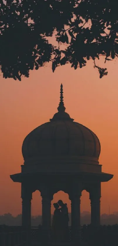 Silhouette of a couple under a dome against a sunset background.