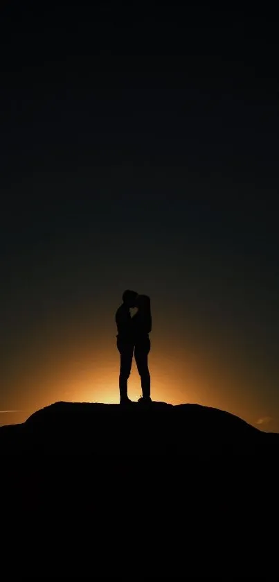 Silhouette of a couple embracing against a sunset backdrop.