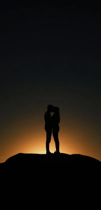 Silhouette of a couple embracing at sunset, creating a romantic scene.