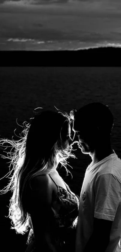 Silhouette of a couple at sunset near a tranquil lake.