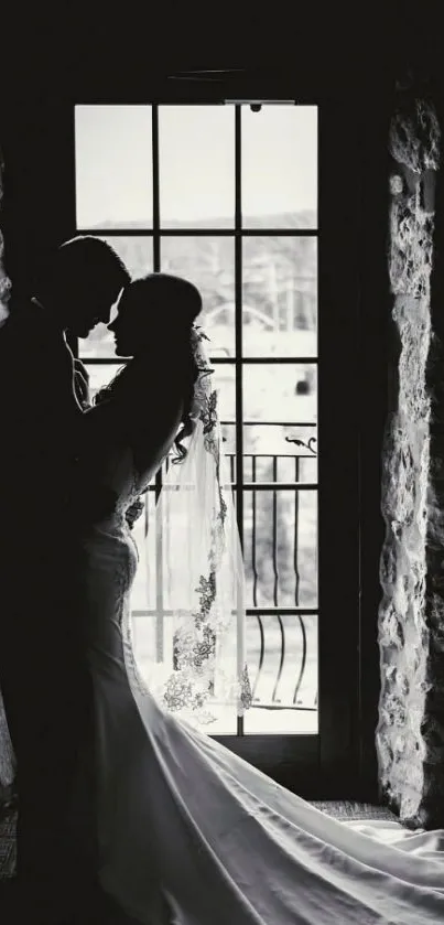 Silhouette of couple in wedding attire by a window, in black and white.