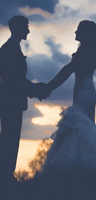 Silhouetted couple holding hands at sunset with dramatic sky.