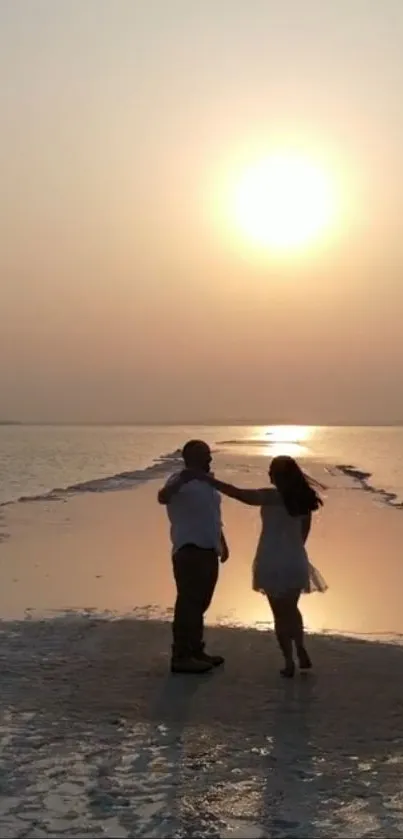 A couple walking on the beach during a warm orange sunset.