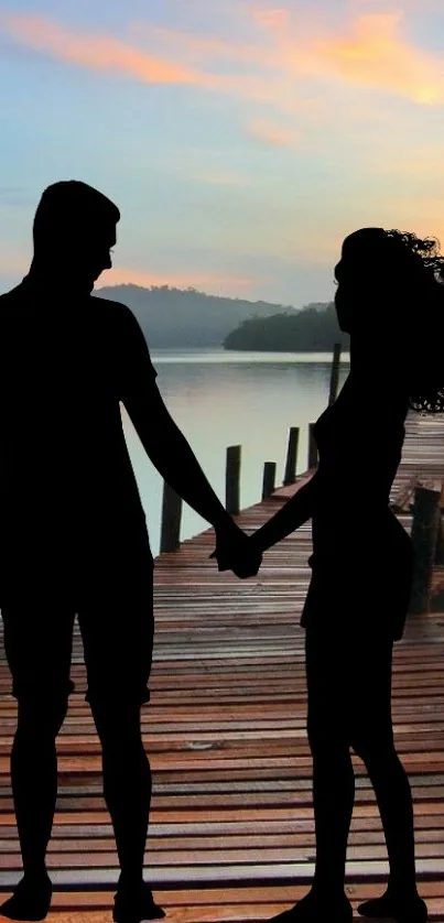 Silhouette of couple holding hands by a dock at sunset.