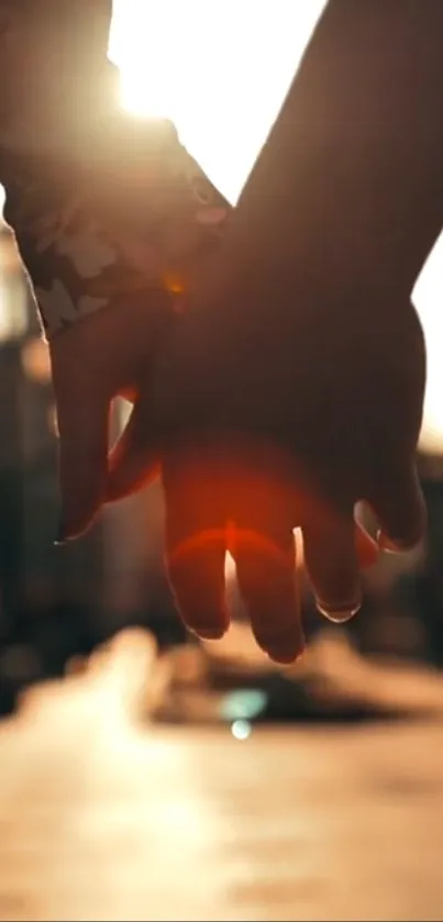 Hands holding against a romantic sunset backdrop, creating a silhouette.