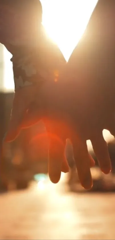 Couple holding hands at sunset with an orange glow.