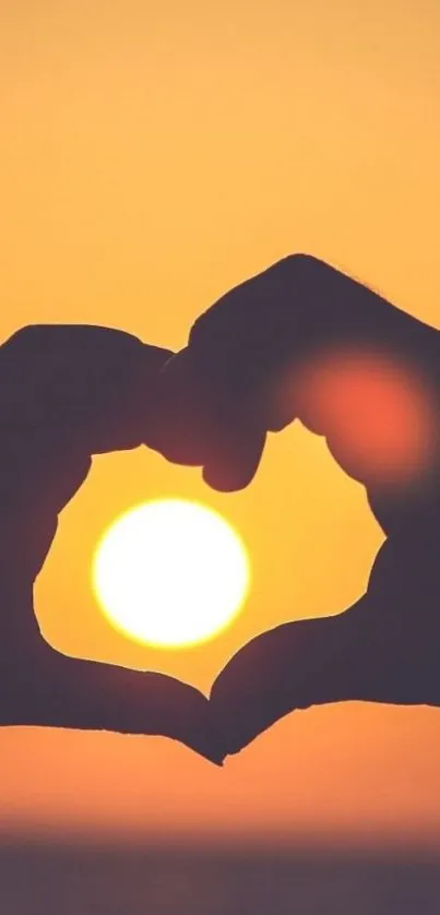 Hands forming a heart around a sunset.