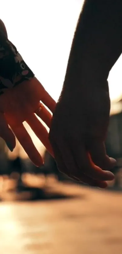 Silhouette of hands holding during sunset with warm peachy background.