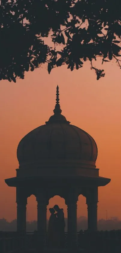 Romantic sunset over a pavilion with silhouettes against an orange sky.