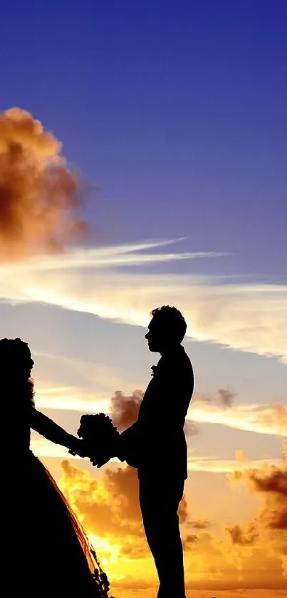 Silhouette of a couple holding hands at sunset with vibrant sky.