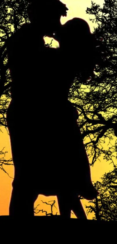 Silhouette of a couple kissing at sunset with tree branches.