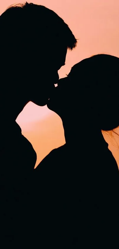 Silhouette couple kissing at sunset with vibrant orange sky.