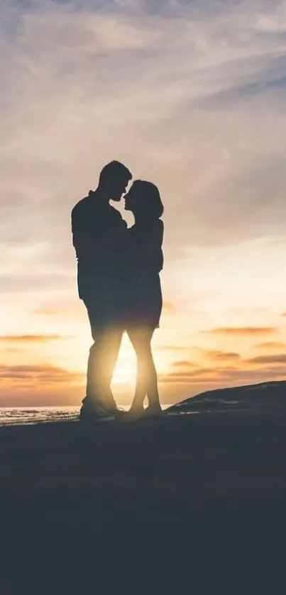 Silhouette of couple embracing at sunset by the ocean.