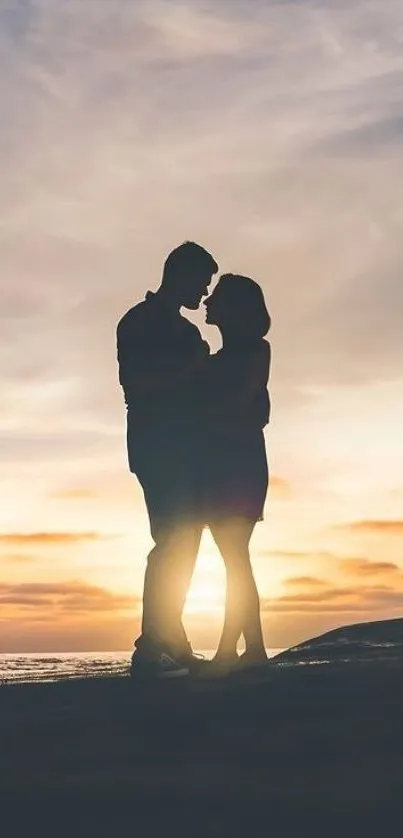 Silhouette of a couple embracing at sunset by the ocean with a serene sky backdrop.