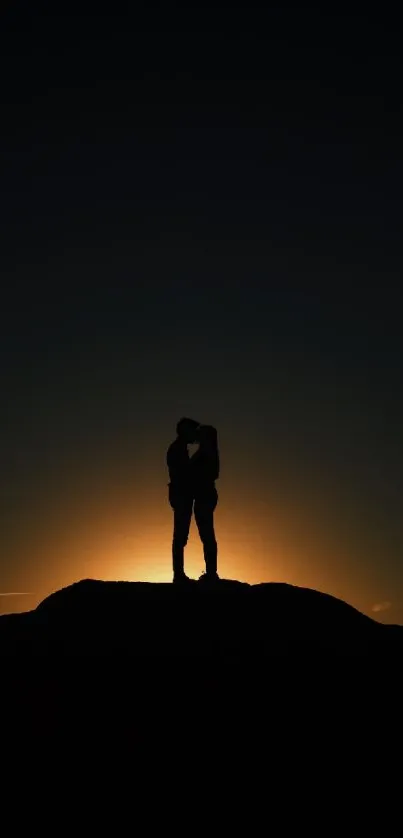 Silhouetted couple kissing at sunset with a warm, glowing horizon.