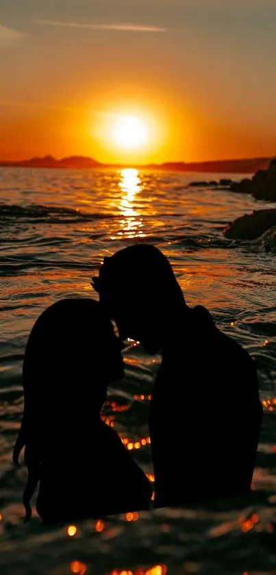 Romantic silhouette of couple at sunset on ocean's edge.