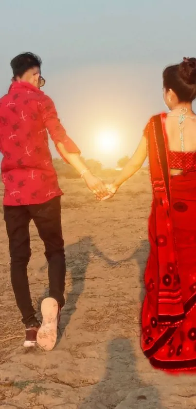 Couple walking hand in hand at sunset on a beach, glowing with red hues.