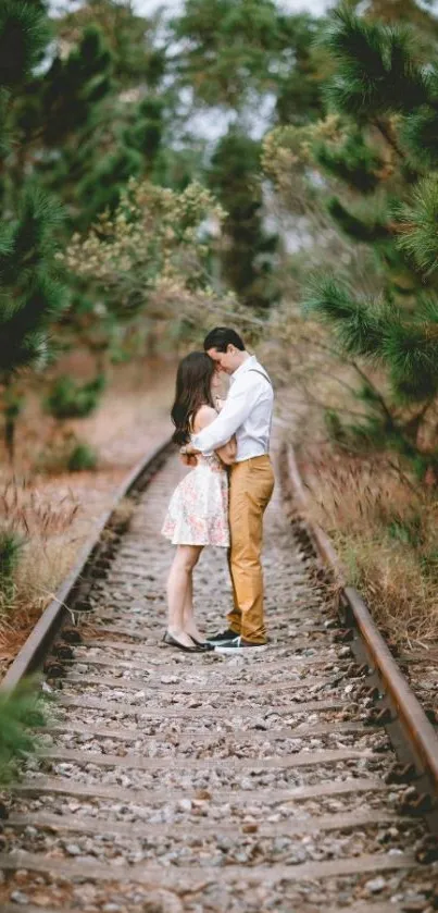 Couple embracing on train tracks in nature.