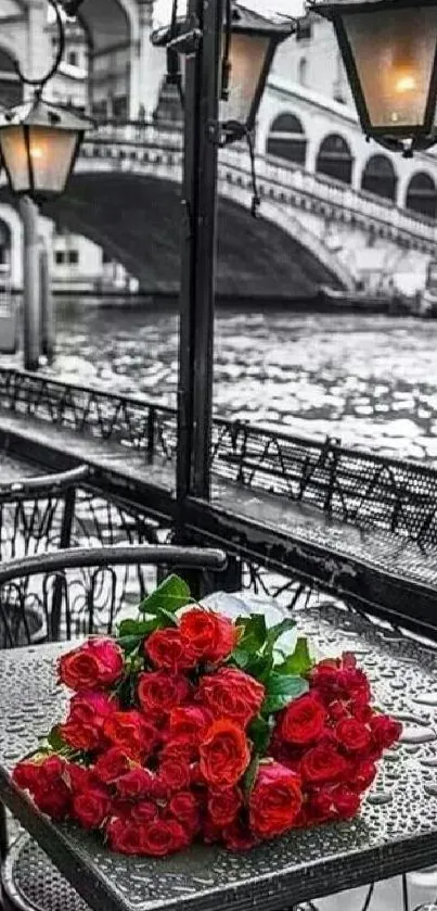 Red roses on a Venice table with a scenic bridge view.