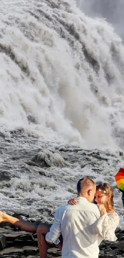 Romantic couple kissing near a waterfall with an umbrella.