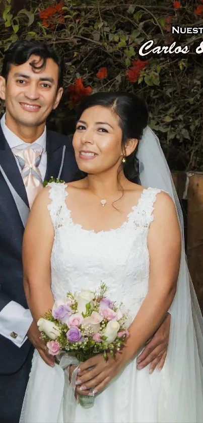 Happy wedding couple in elegant attire with floral backdrop.