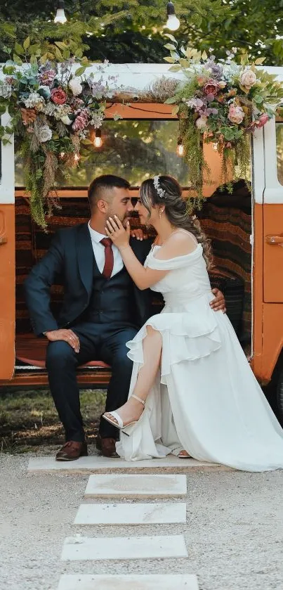 Wedding couple sitting beside orange van with flowers.