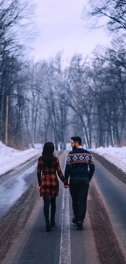 Couple walking hand-in-hand through a snowy winter forest.