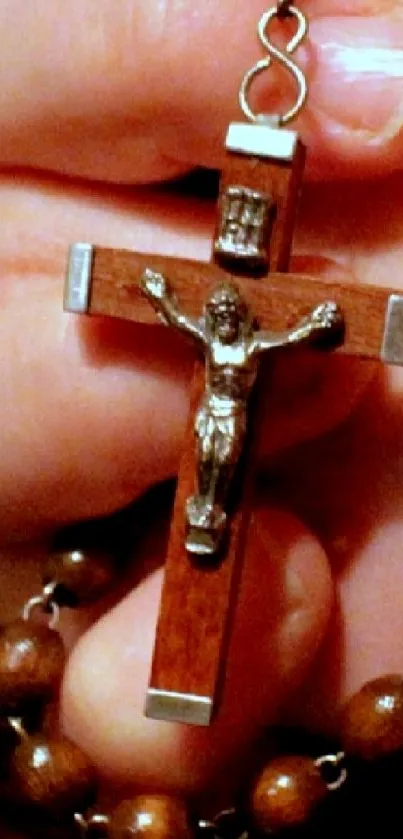 Hands holding a rosary with wooden beads.