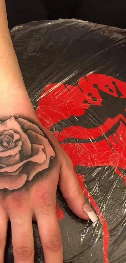 Rose tattoo on hand with red accents.