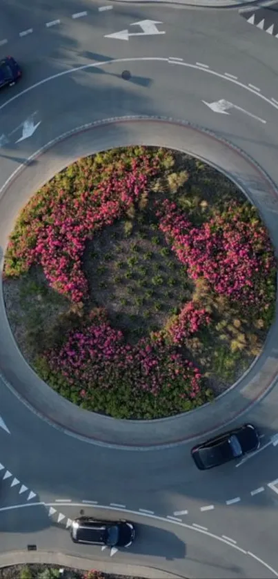 Aerial view of a roundabout with flower center and surrounding cars.