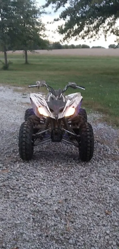 ATV on gravel path in countryside with trees.