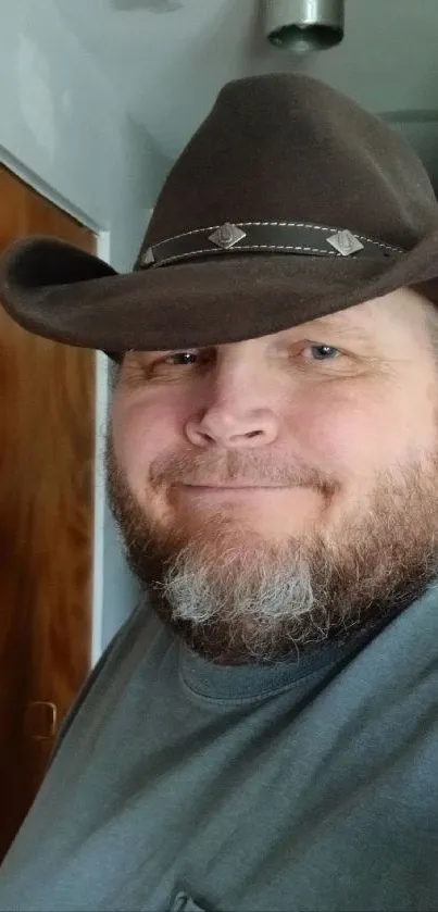 Bearded man in a cowboy hat, indoors with a rustic setting.