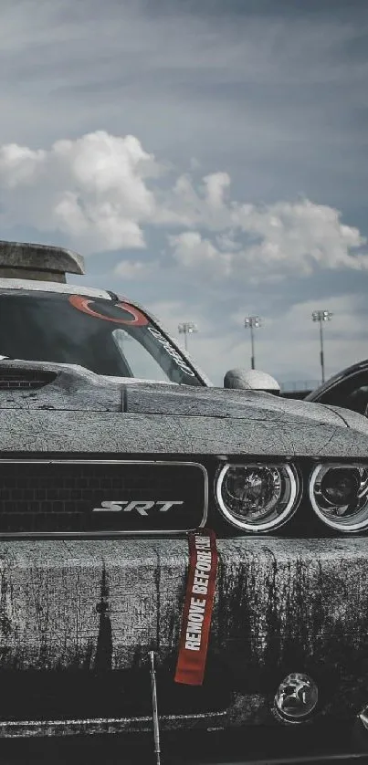 Gritty Dodge Challenger parked under a cloudy sky, highlighting muscle car design.