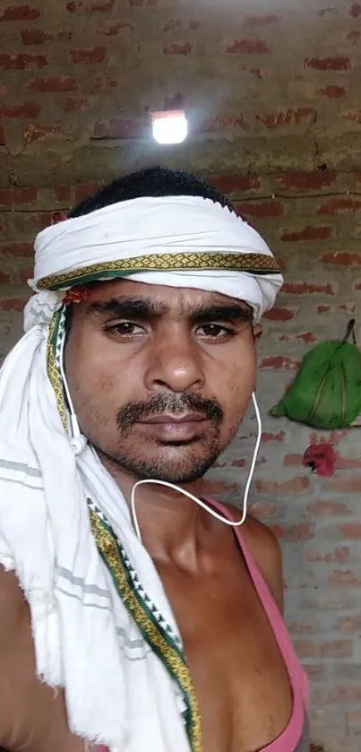 Portrait of a man in traditional rural attire with a brick wall background.