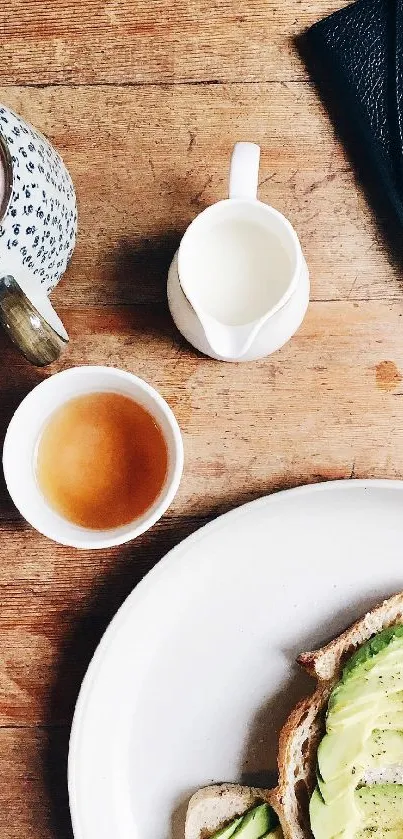 Overhead view of avocado toast, tea, and accessories on a rustic wooden table.