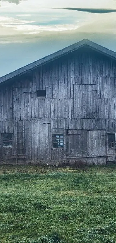 Rustic wooden barn in a tranquil rural landscape with a cloudy sky.