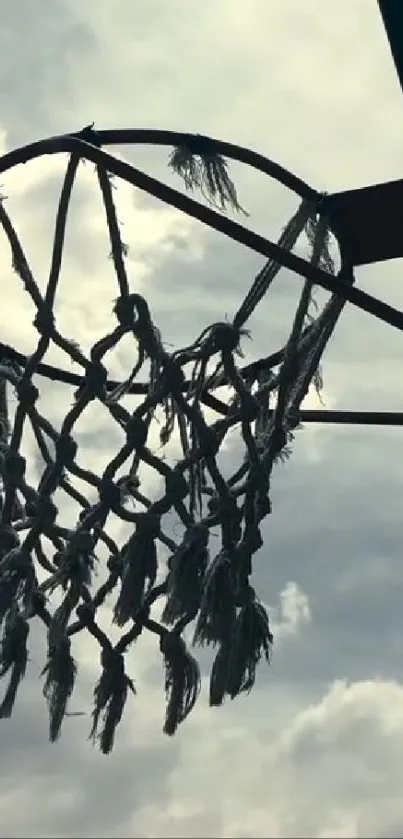 Silhouette of a rustic basketball hoop against a cloudy sky.