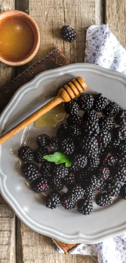 Rustic plate with blackberries and honey dipper on wooden table.