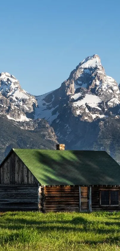 Rustic cabin with mountains in the background under a clear blue sky.