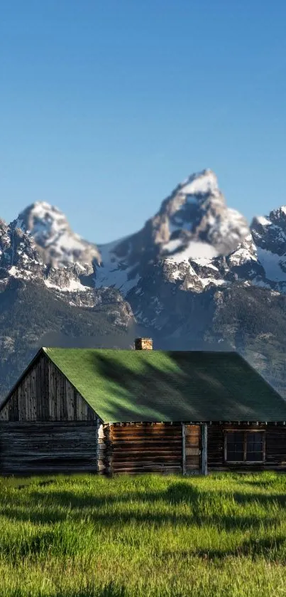 Rustic cabin with green roof and mountain peaks in the background.