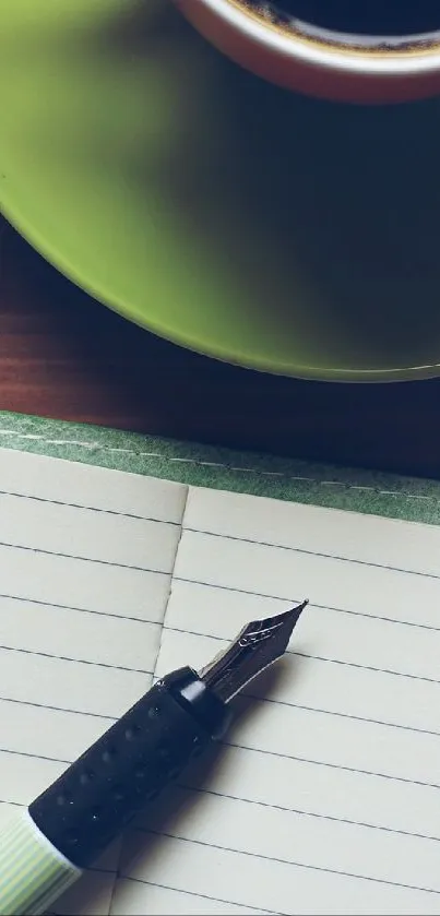 Rustic desk scene with notebook, pen, and green coffee cup on wooden surface.