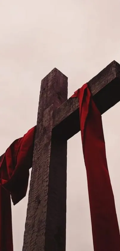 Wooden cross with red cloth against a soft sky.