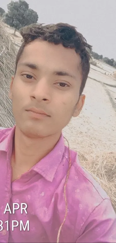 Selfie in a rustic farm setting, featuring a pink shirt and serene countryside backdrop.