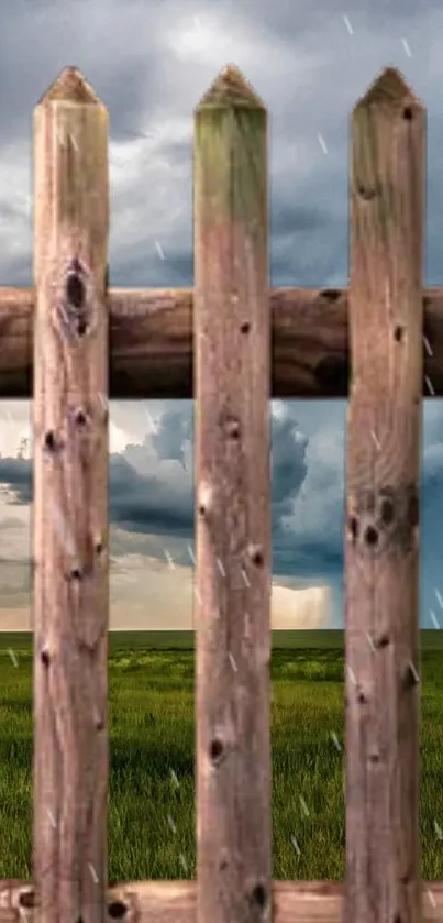 Rustic wooden fence with stormy sky and grassy field.