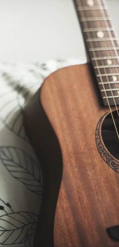 Wooden acoustic guitar resting on cozy pillow.